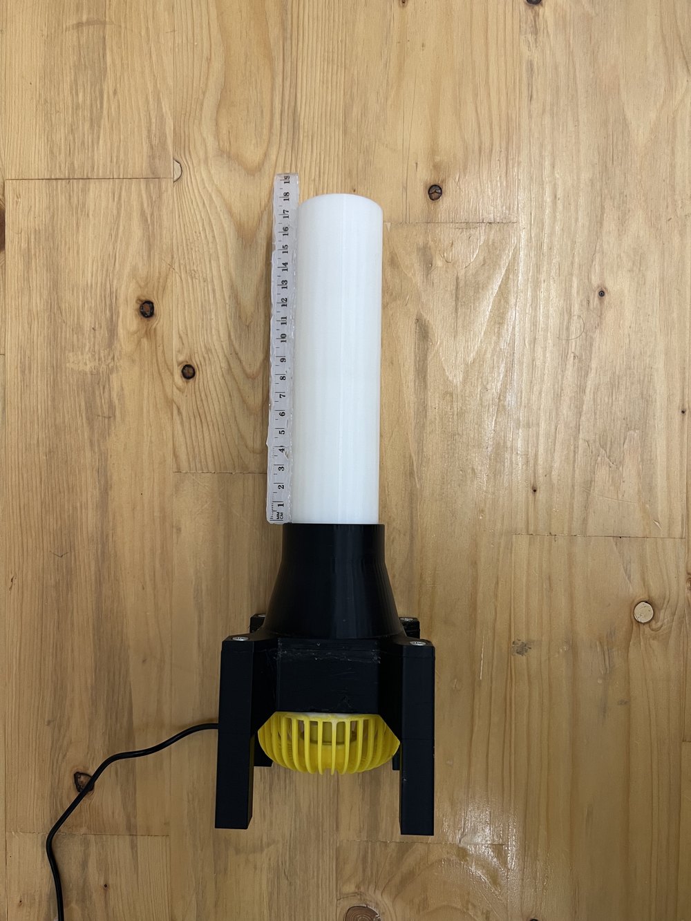The airflow assembly upright: a white tube with a measuring scale along it, mounted on a black 3D-printed nozzle with the yellow fan visible underneath.